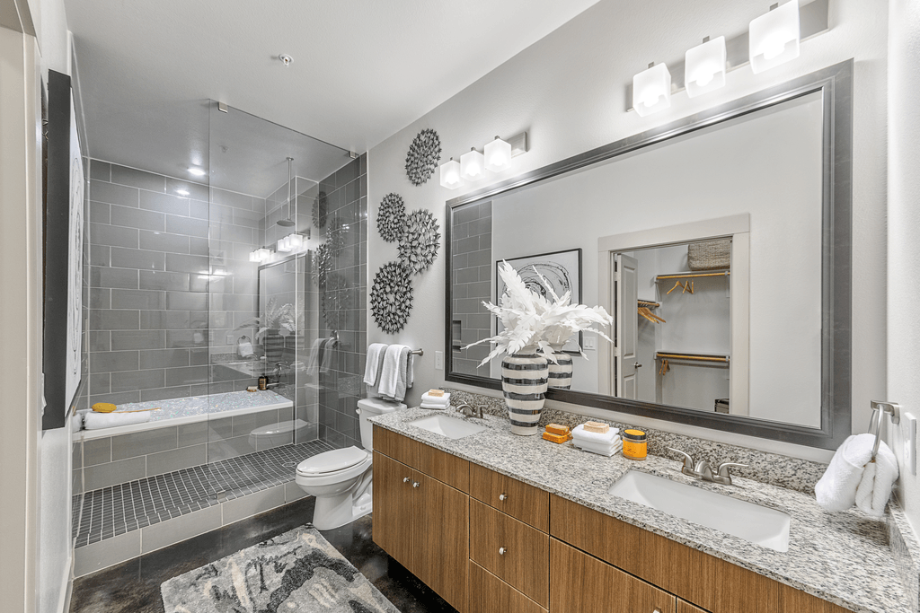 A bathroom with a toilet, sink, and mirror.
