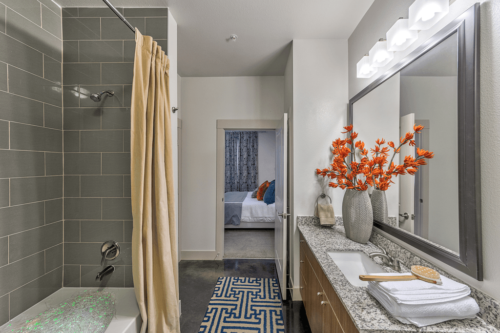 A bathroom with a shower, sink, and mirror.