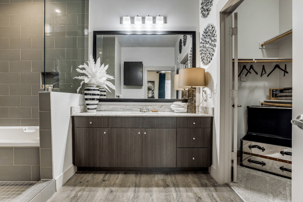 A modern bathroom with a large mirror and a wooden vanity.