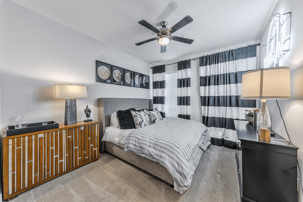 A bedroom with a bed, nightstand, and a ceiling fan.