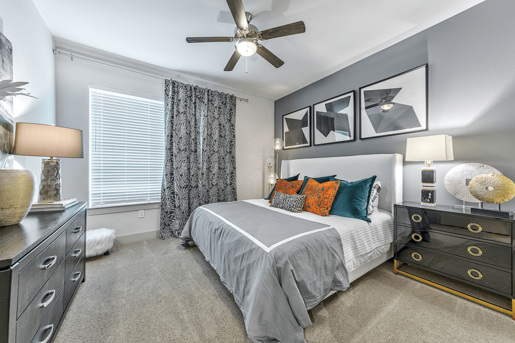 A bedroom with a bed, dresser, and ceiling fan.