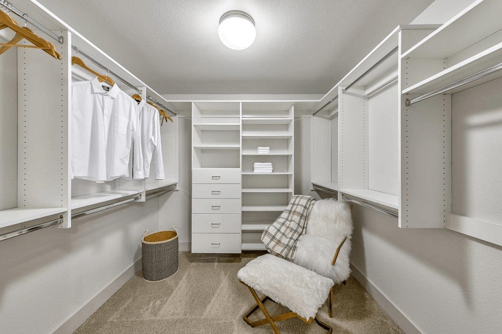 A white closet with a chair and a trash can.