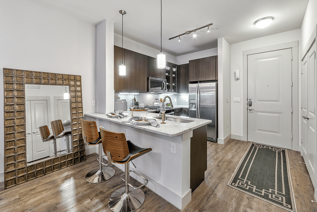 A kitchen with a white countertop and brown chairs.
