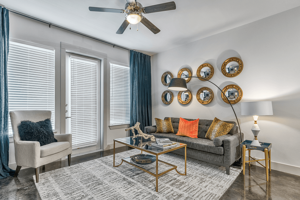 A living room with a grey couch, a chair, a coffee table, and a ceiling fan.