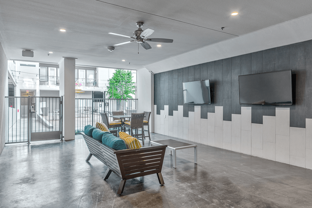 A modern living room with a wooden bench and a ceiling fan.
