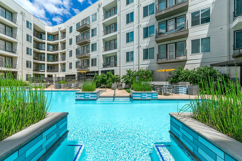 A large swimming pool in front of apartment buildings.