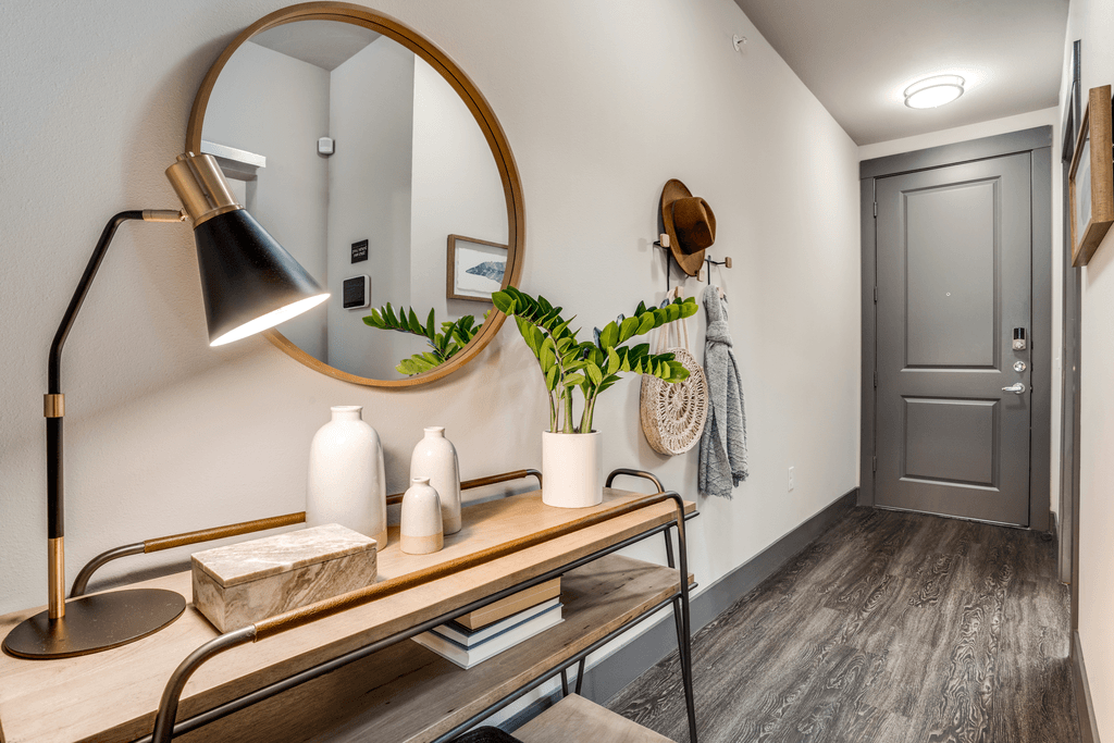 A mirrored console table with a lamp and a plant on it.