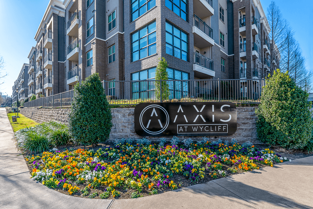 Axis at Wycliffe is a modern apartment complex with a well-maintained flower bed in front.