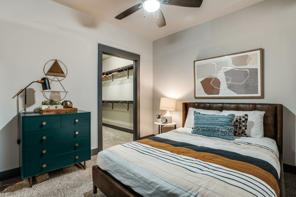 A bedroom with a bed, nightstand, and a dresser with a mirror.