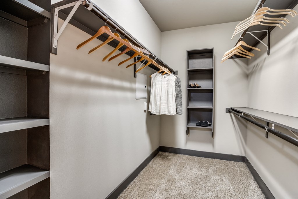 A walk-in closet with shelves and hanging clothes.