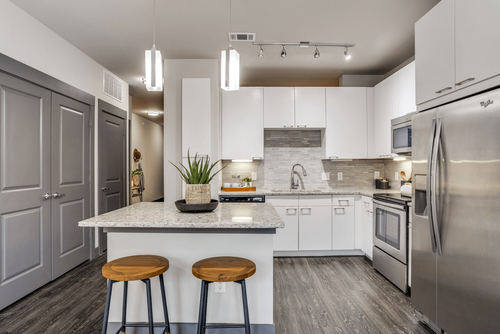 A modern kitchen with a white countertop and stainless steel appliances.