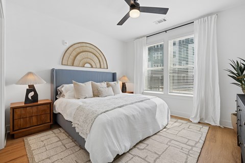 A bedroom with a bed, nightstand, and a ceiling fan.