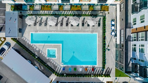 A swimming pool surrounded by a metal fence and umbrellas.