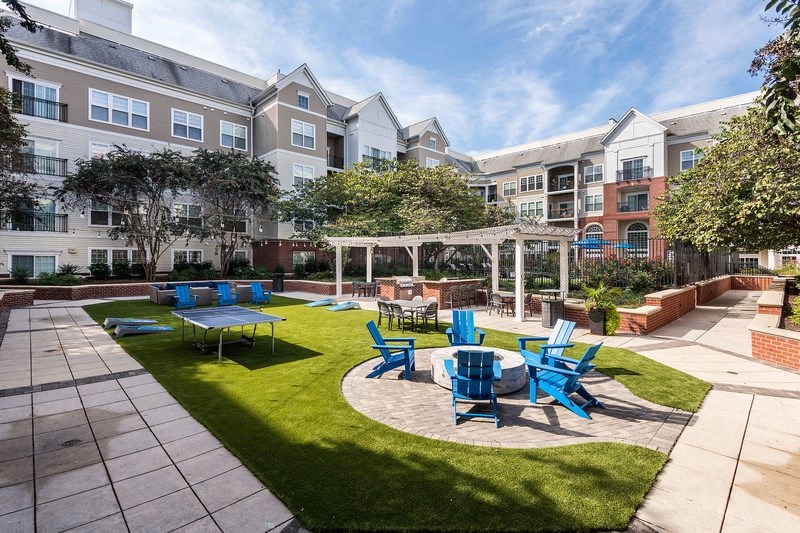 an outdoor courtyard with blue chairs and tables and an apartment building