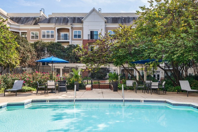 a swimming pool with chairs and umbrellas in front of a hotel