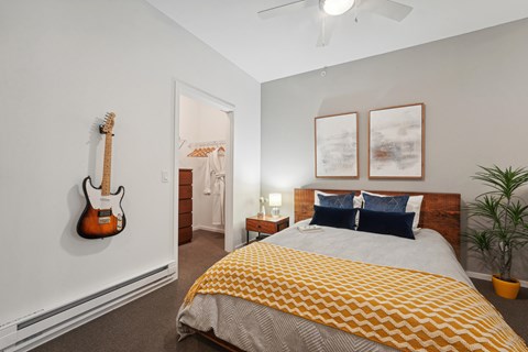 A bedroom with a bed, a guitar, and two pictures on the wall.