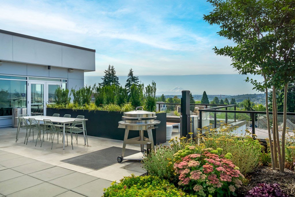 a rooftop terrace with tables and chairs and a view of the ocean