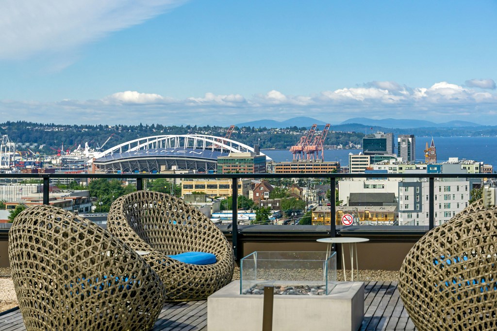 a view of a city and the water from a balcony with chairs