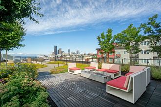 a rooftop deck with furniture and a city in the background