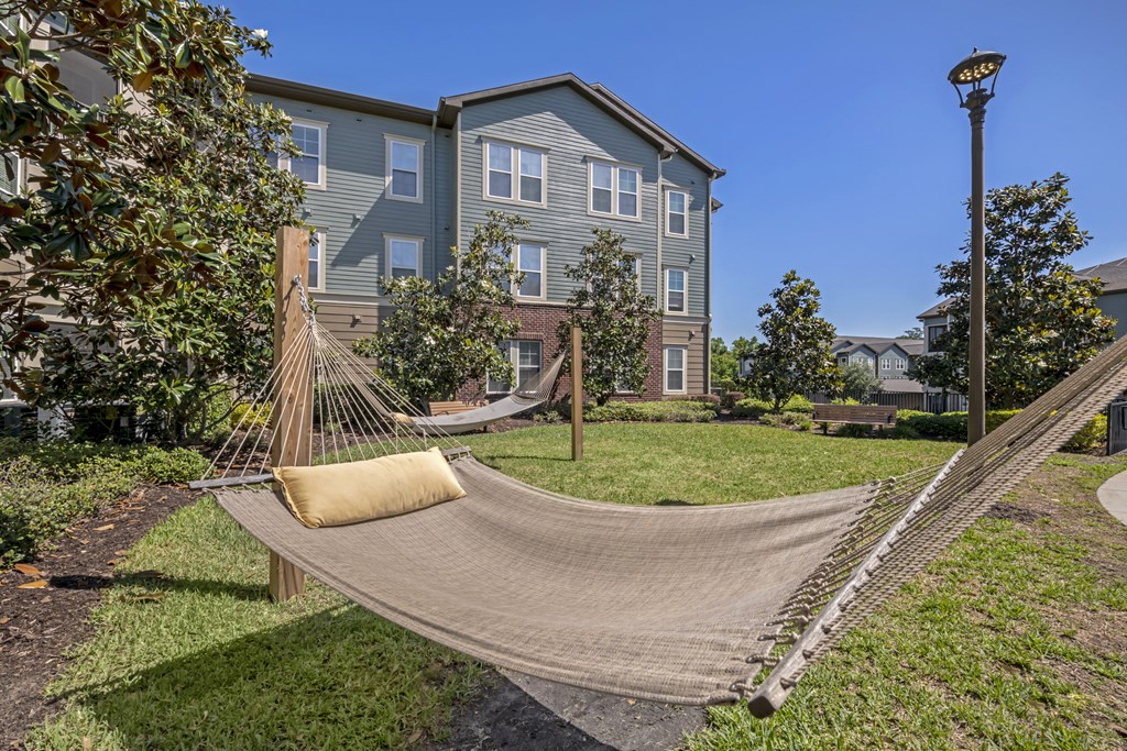 a hammock in a yard in front of an apartment building