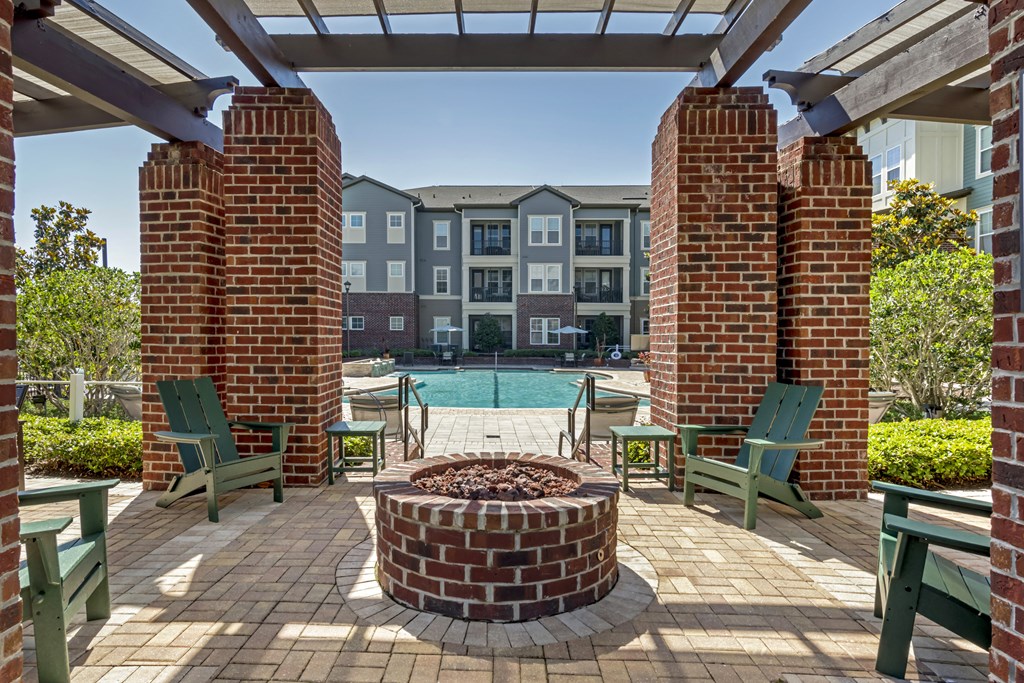 an outdoor patio with a firepit and green adirondack chairs