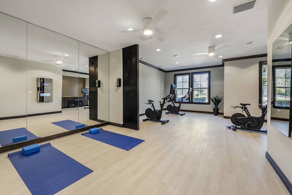 a spacious fitness room with white walls and hardwood flooring