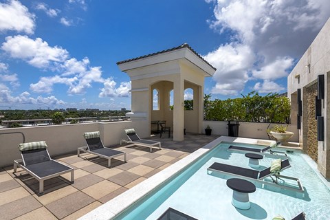 A pool with lounge chairs and a small building.