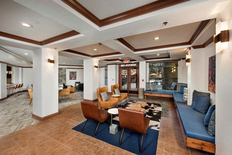 A living room with a blue couch and brown chairs.