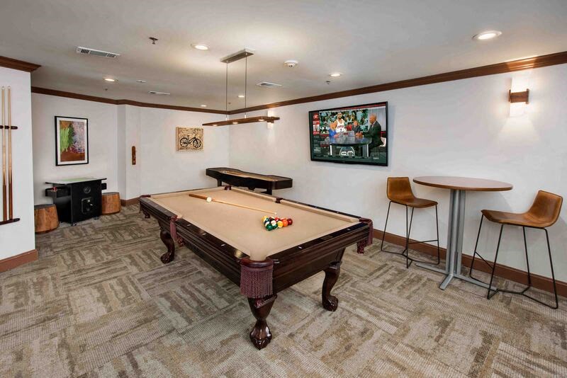 A pool table in a room with a bar stool and a painting on the wall.