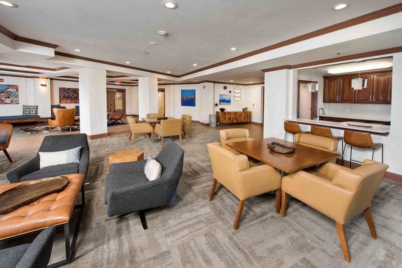 A living room with a grey carpet and brown leather furniture.