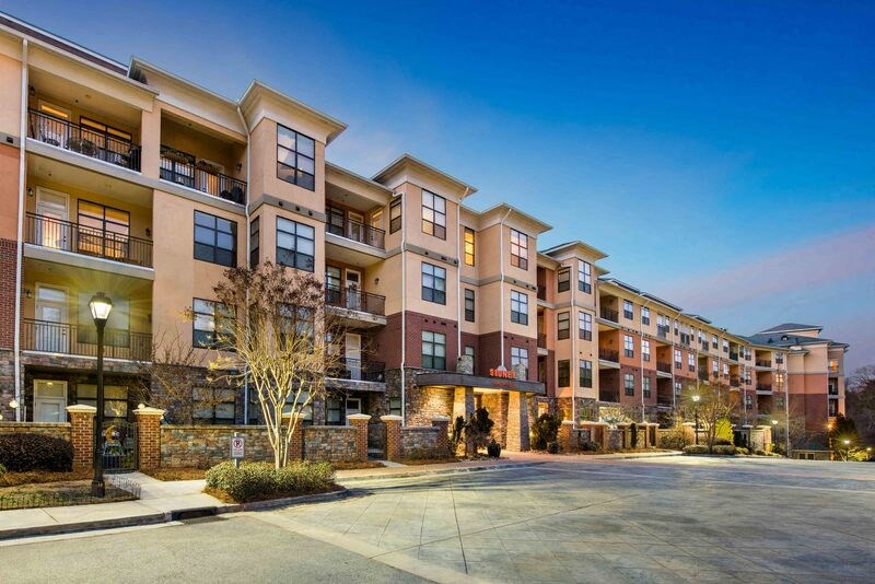 Apartment complex with a parking lot in front.