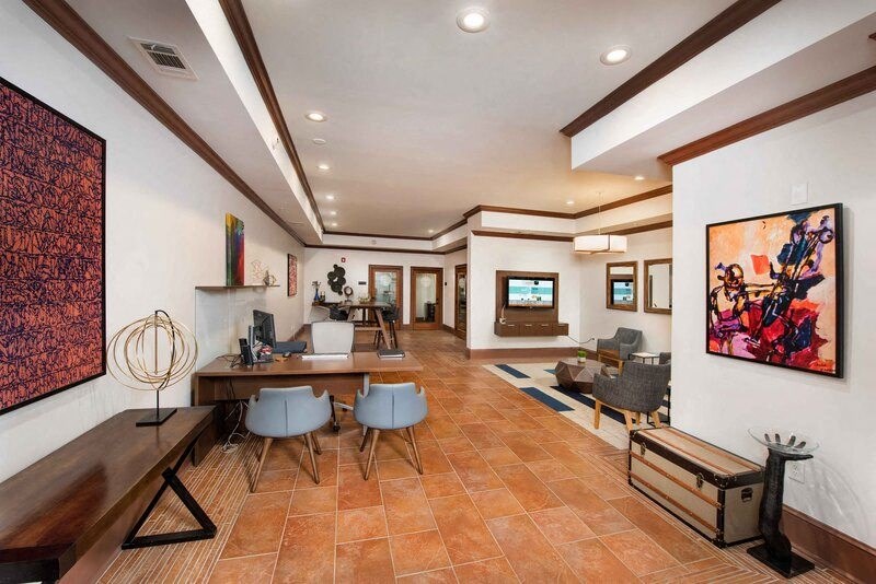 A living room with a brown tile floor and a large painting on the wall.