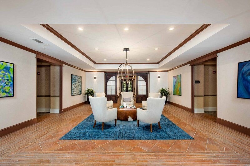 A spacious room with a blue rug and a chandelier.