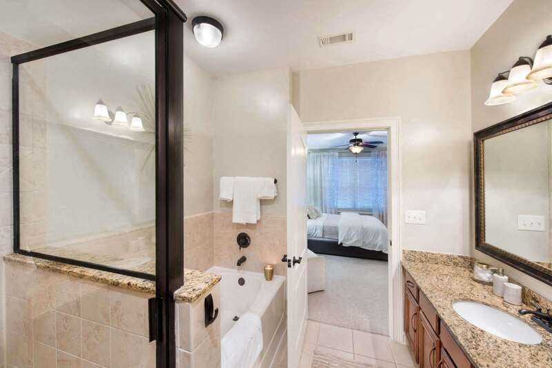 A bathroom with a glass shower door and a marble countertop.