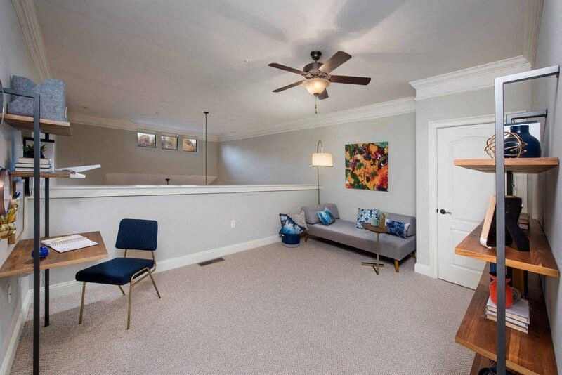 A living room with a grey couch, a blue chair, and a wooden shelf.