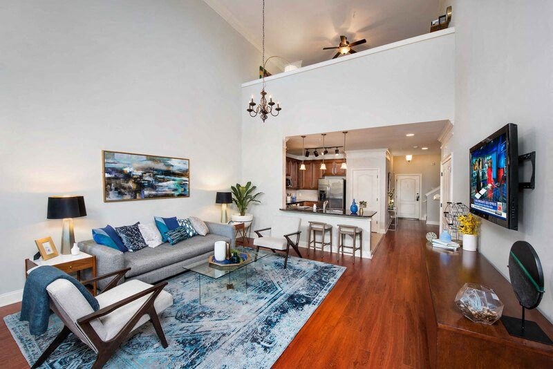 A living room with a grey couch and a blue rug.