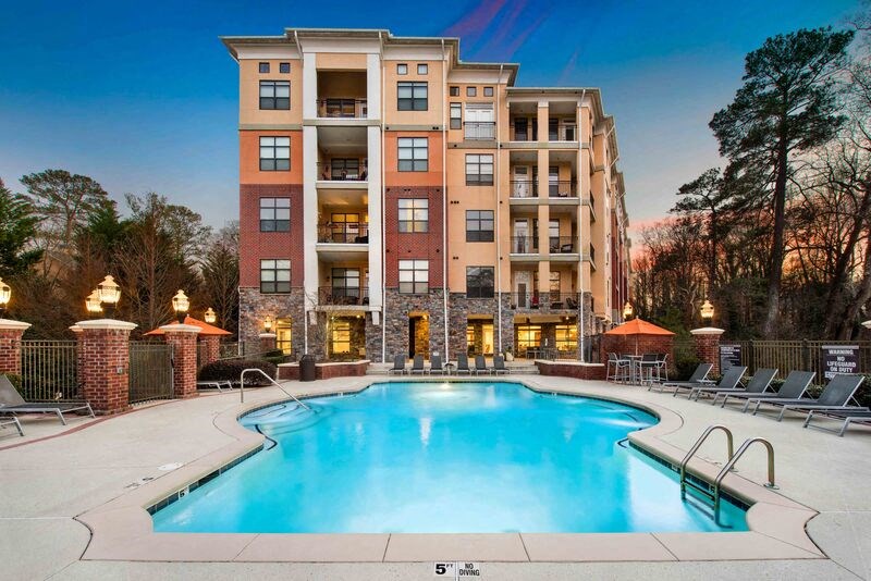 A large apartment building with a swimming pool in front.