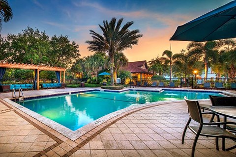 a swimming pool with tables and chairs around it