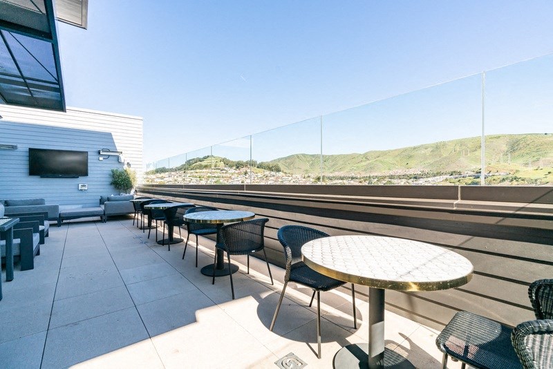 a patio with tables and chairs on a rooftop overlooking a train