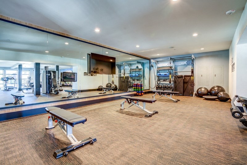 a workout room with weights and exercise equipment in a large glass walled gym