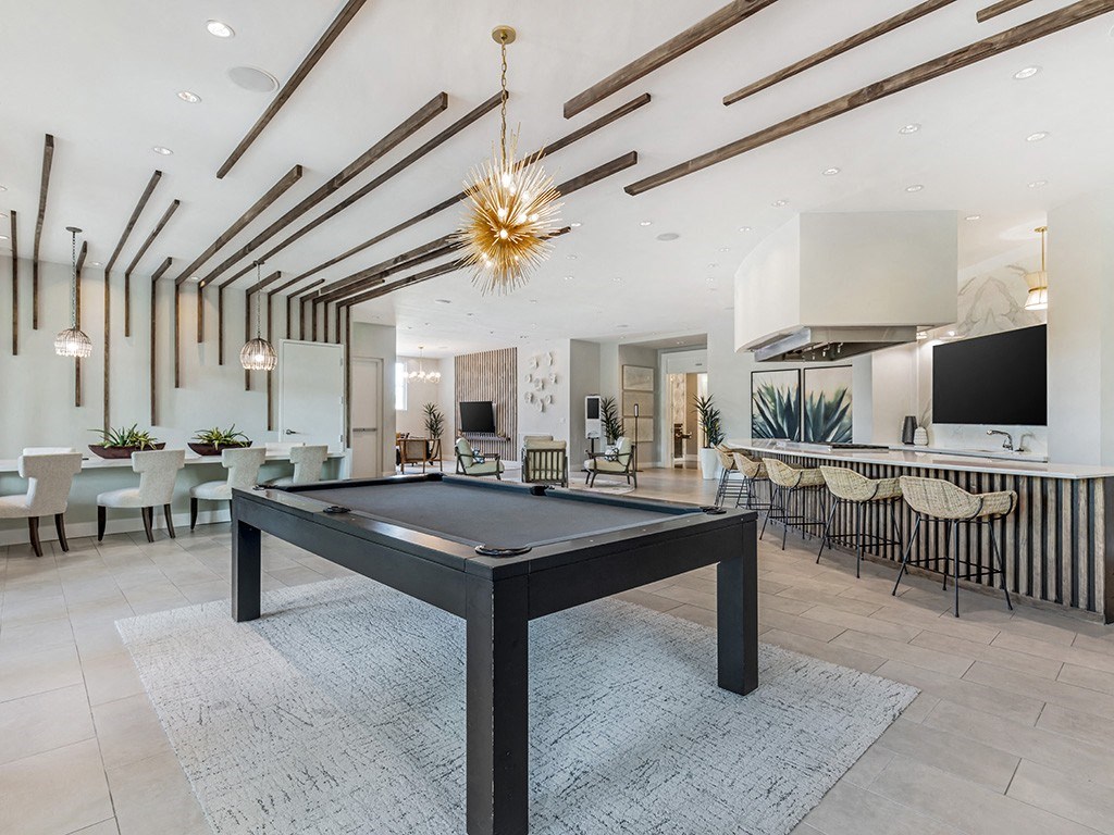 a pool table in a living room with a bar and a television