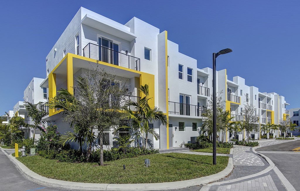 A white and yellow apartment building with a clear blue sky in the background.