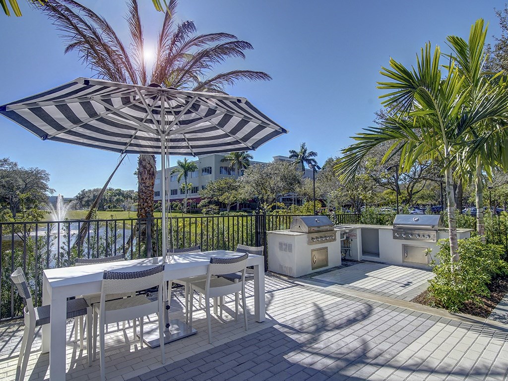 A patio with a table and chairs under a striped umbrella.