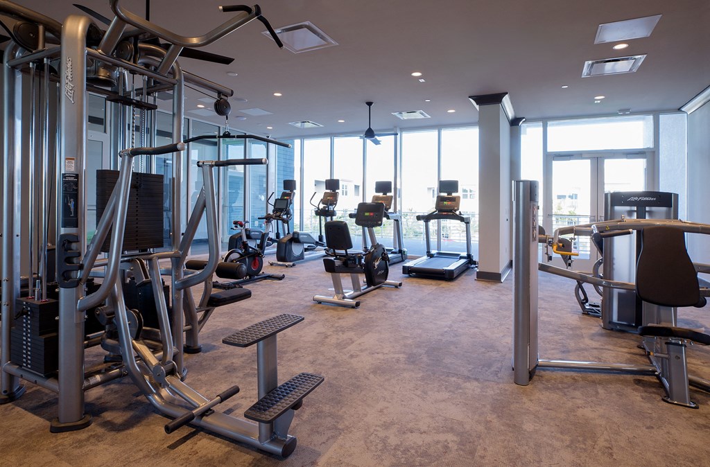 a spacious fitness room with cardio equipment and floor to ceiling windows