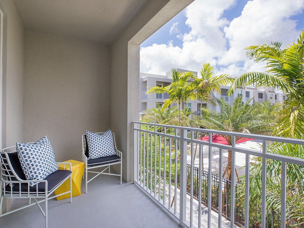 A balcony with two chairs and a table.