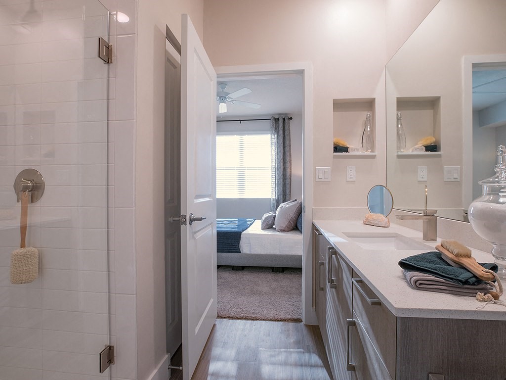 A bathroom with a white tiled shower and a white sink.