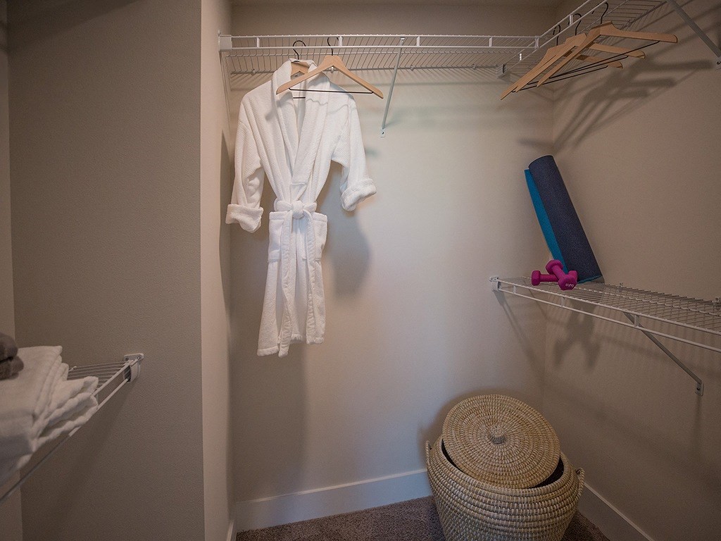 A white robe is hanging on a clothes rack in a room.