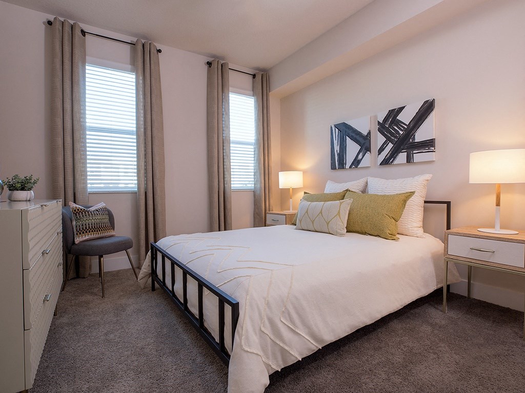 A bedroom with a large bed, a chair, and a painting on the wall.