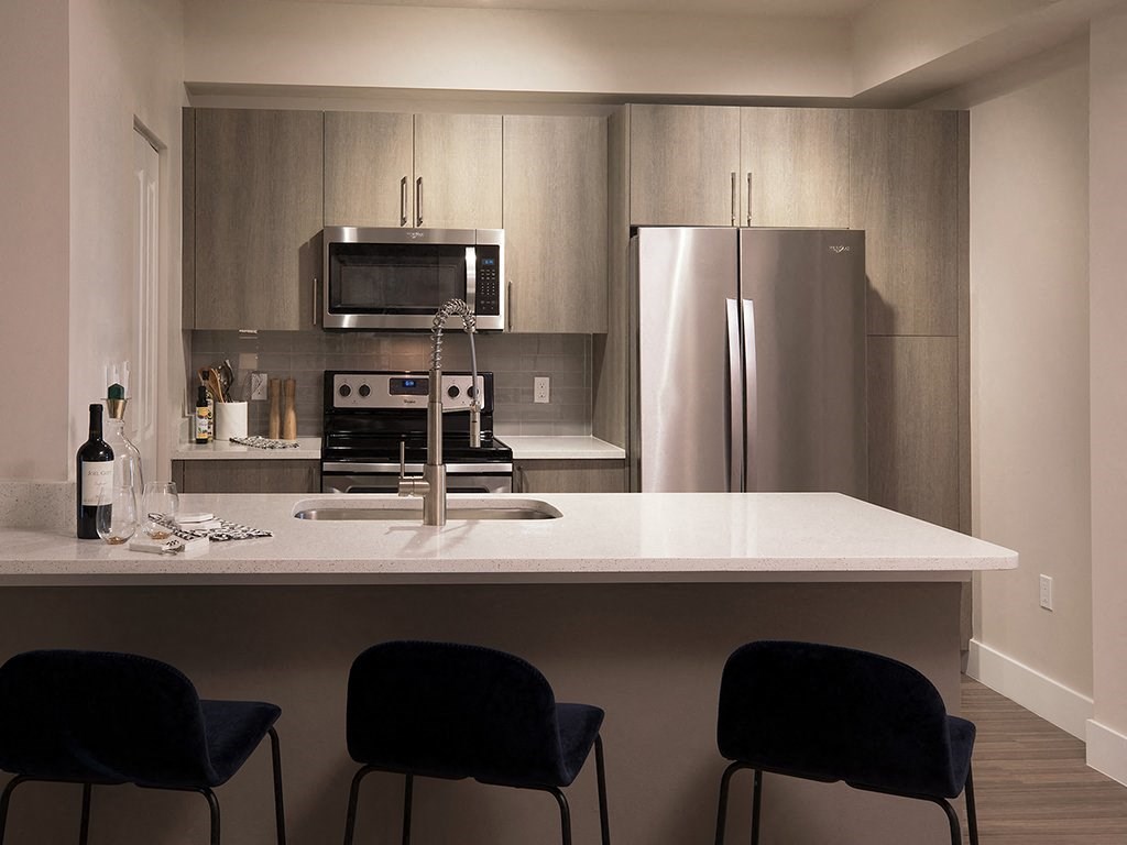 A modern kitchen with a white countertop and stainless steel appliances.