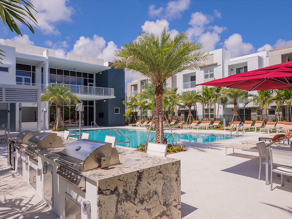 A poolside area with a grill and chairs.